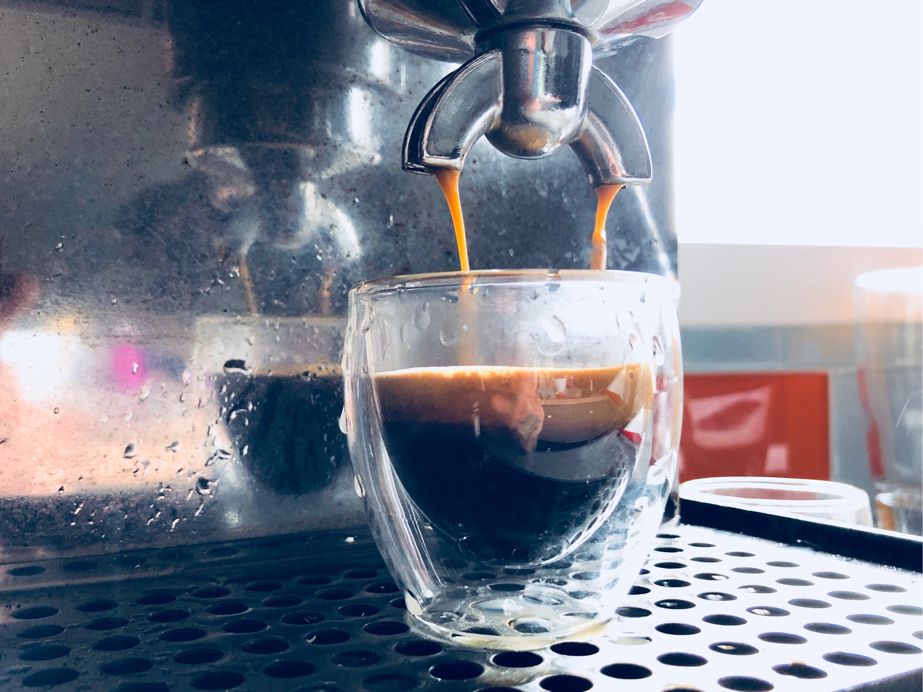 Photo of a glass espresso cup being filled under a portafilter.  