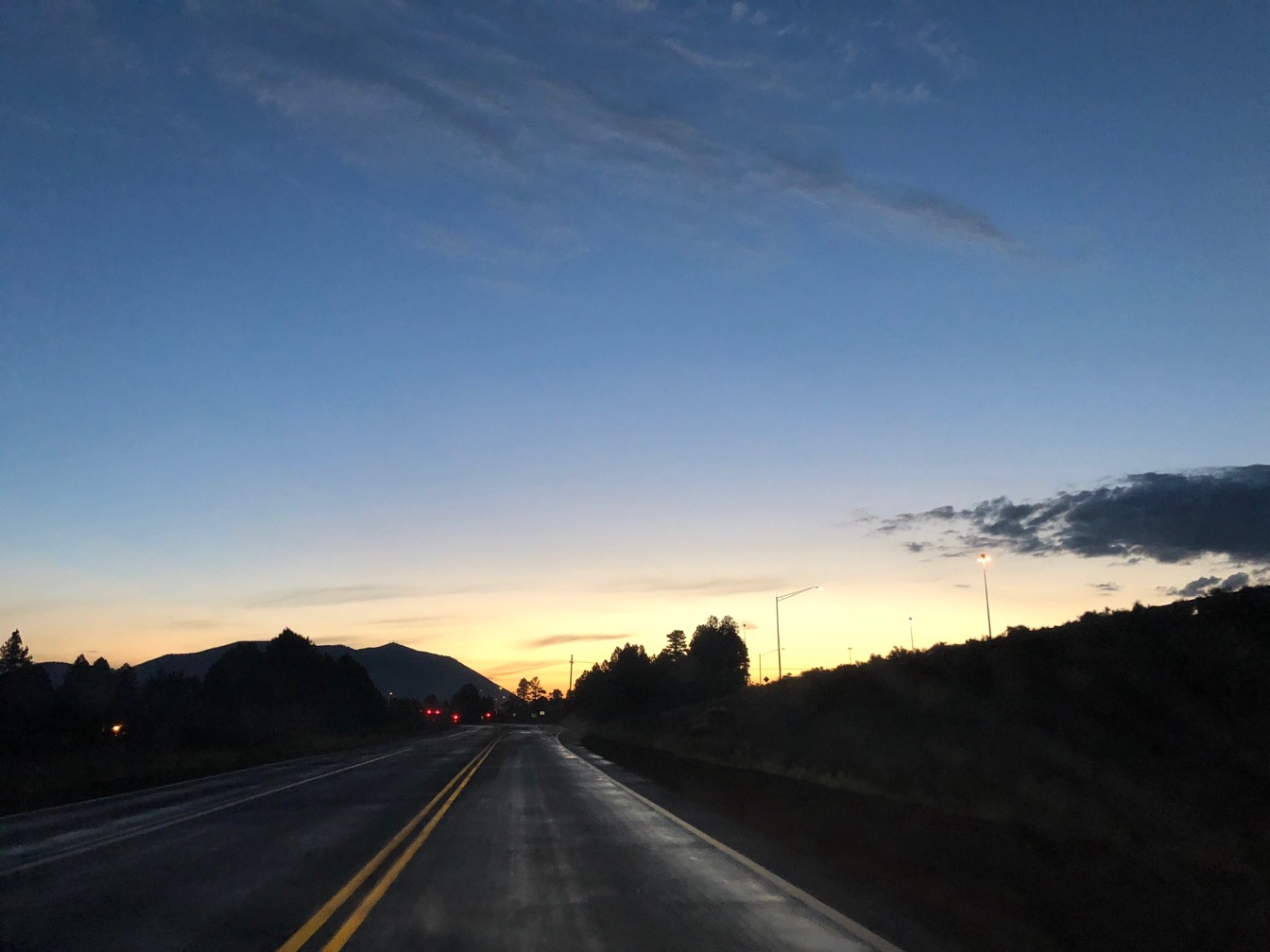 Photo of an early morning stretch of road, with a bit of sunrise on the horizon.  