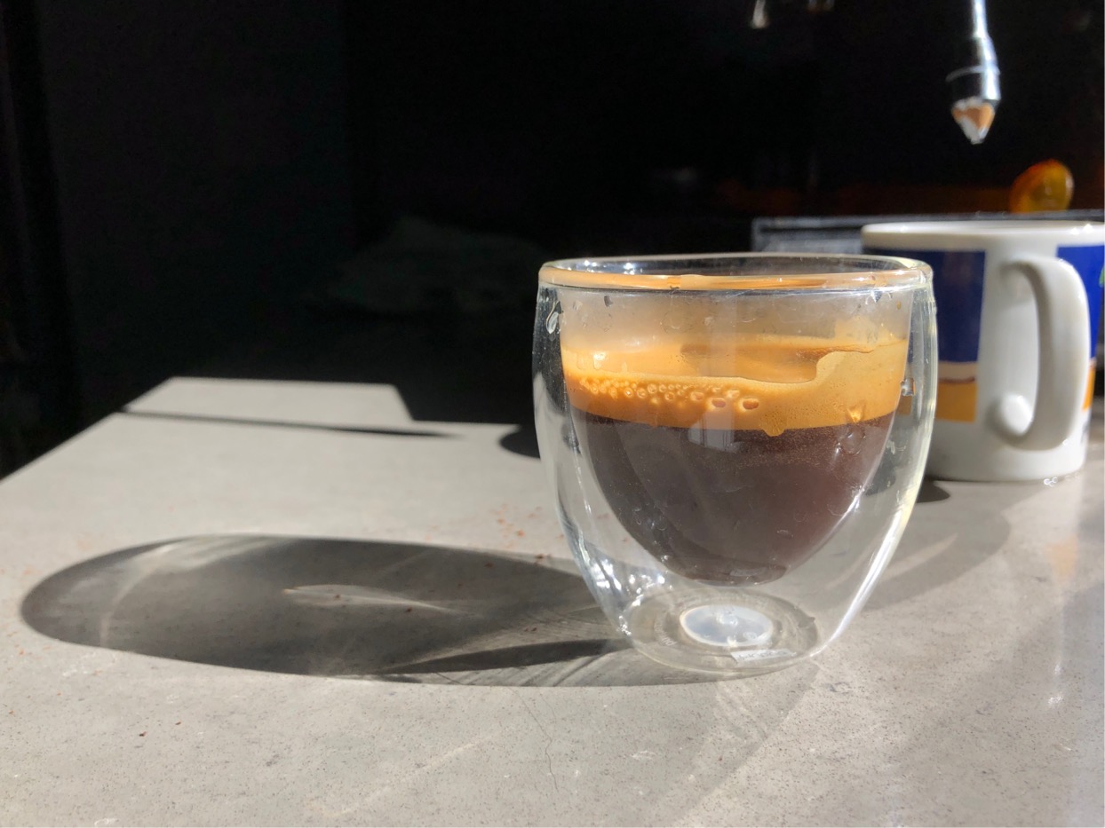 Photo of a shot of espresso in a small clear glass.  