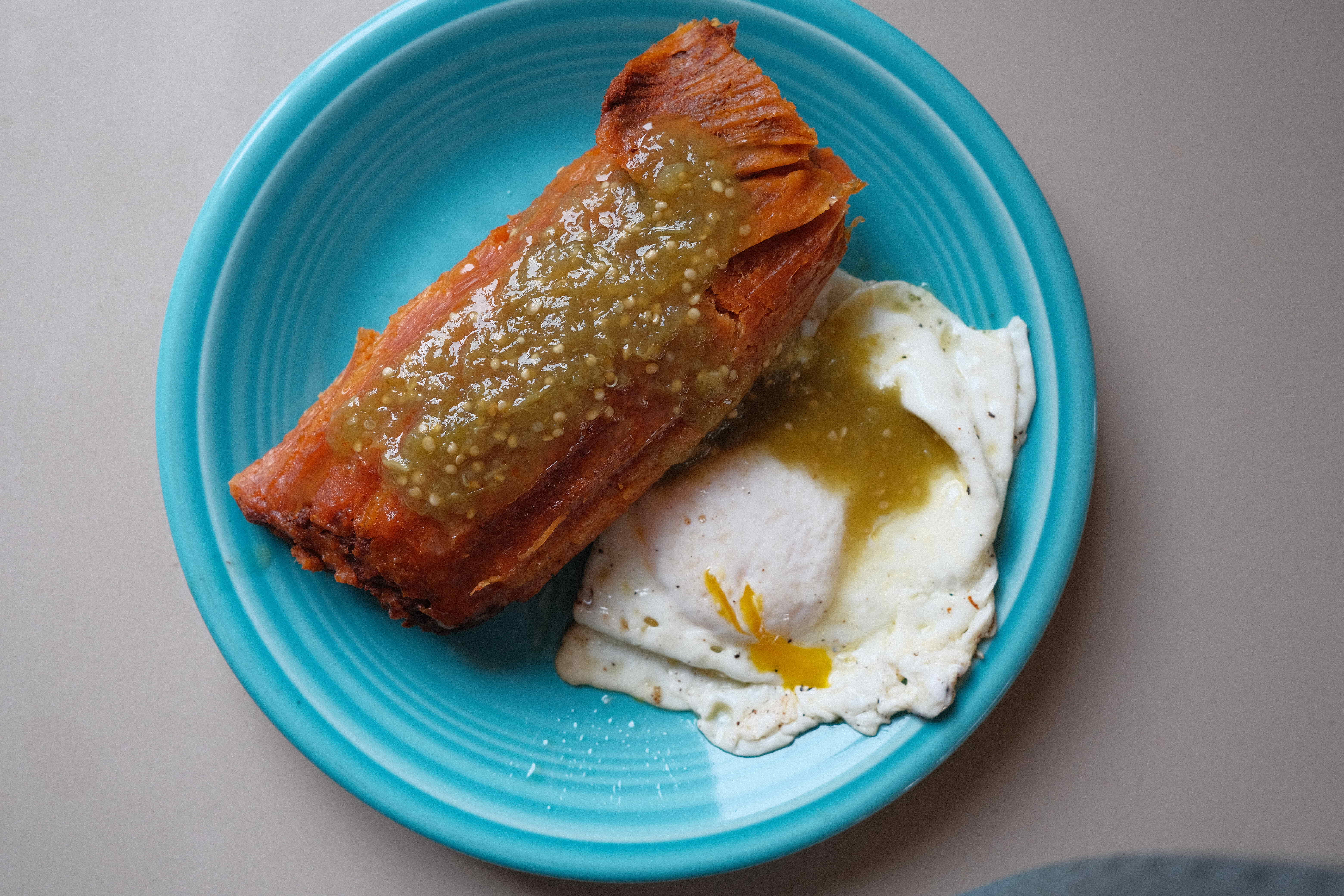 Photo of a red tamale and a fried egg on a light blue plate 
