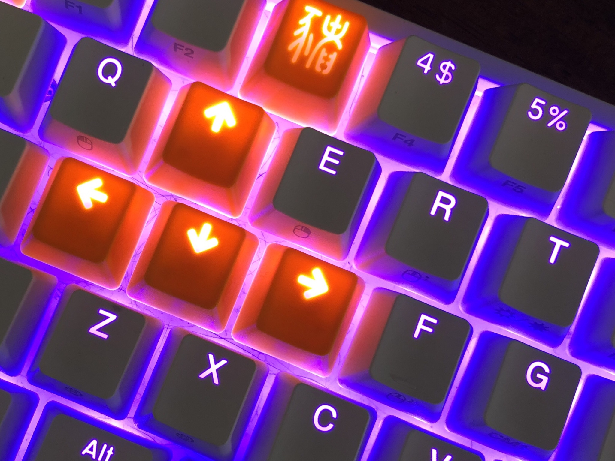 Photo of a keyboard backlit with purple, with several bright orange key caps  