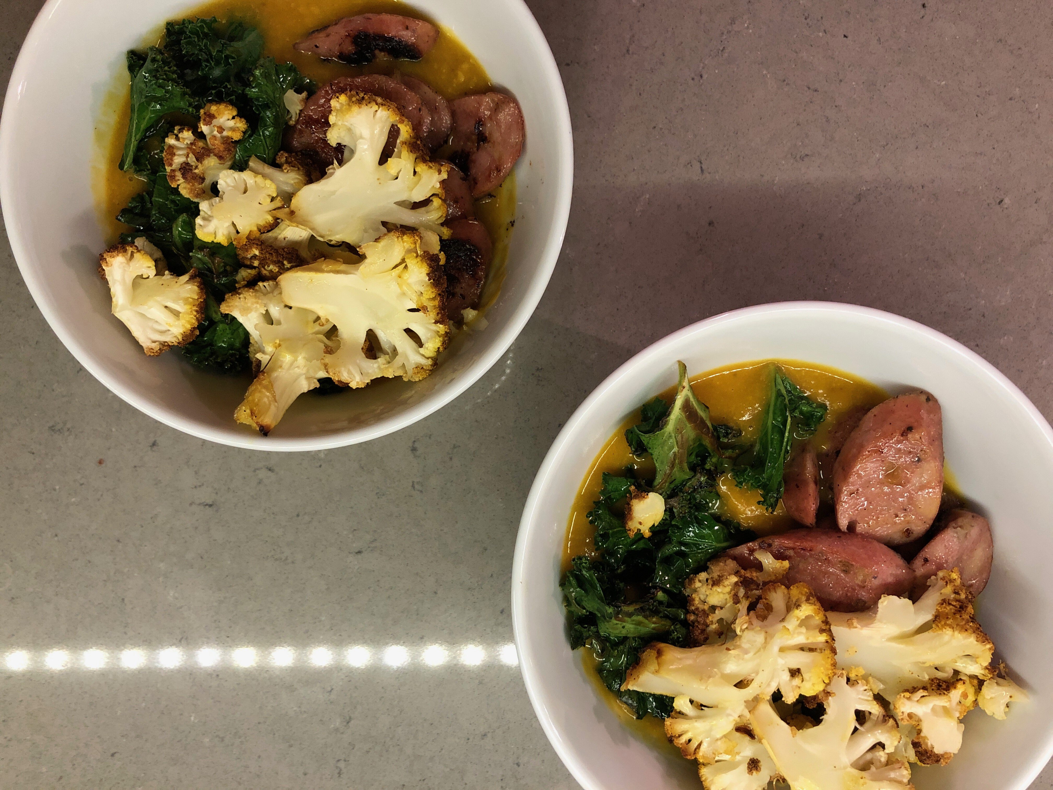 Photo of a creamy soup topped with kale and roasted-browned cauliflower. 
