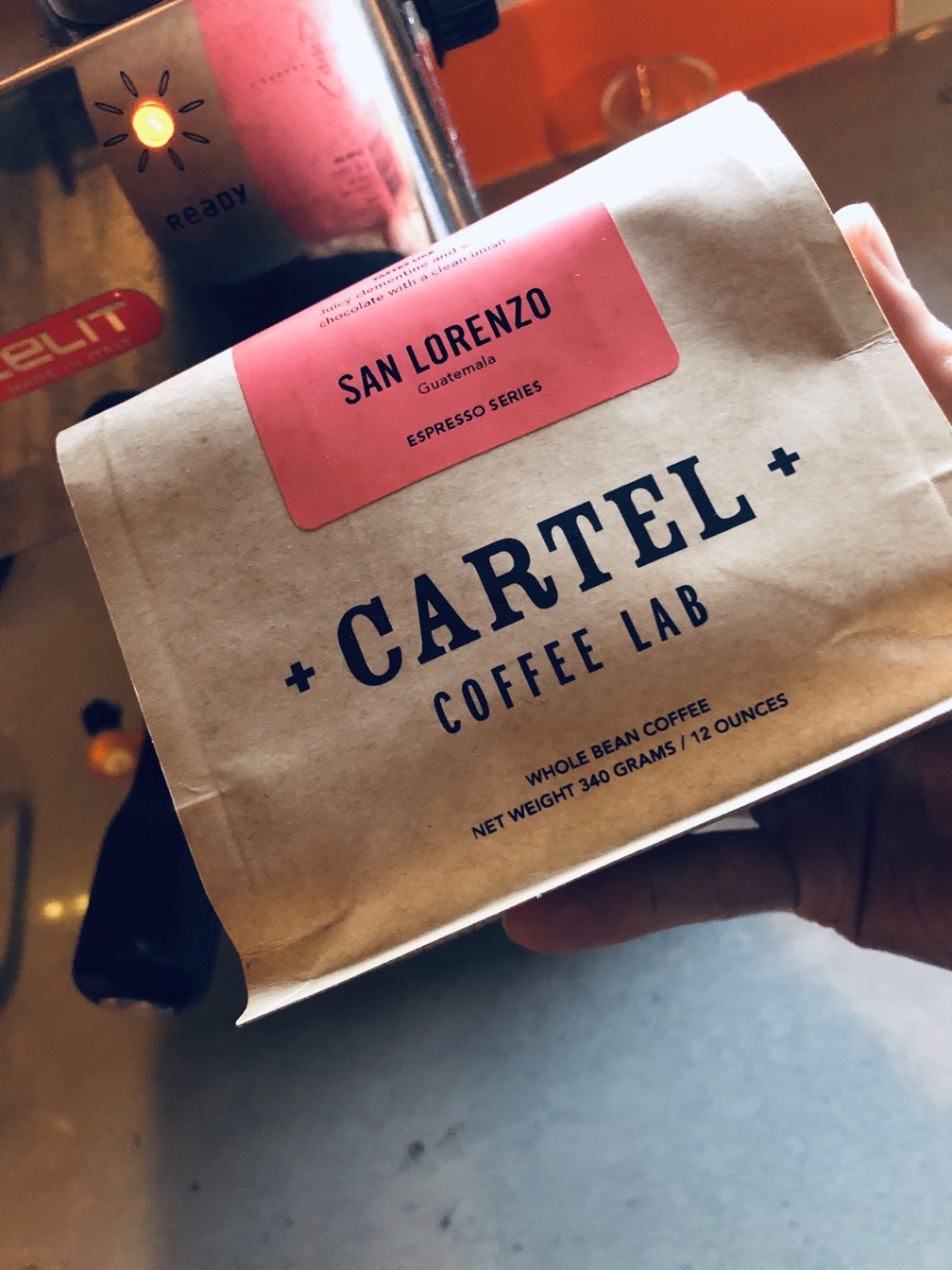 A bag of whole coffee beans with a bright orange label from Cartel Coffee Lab.  