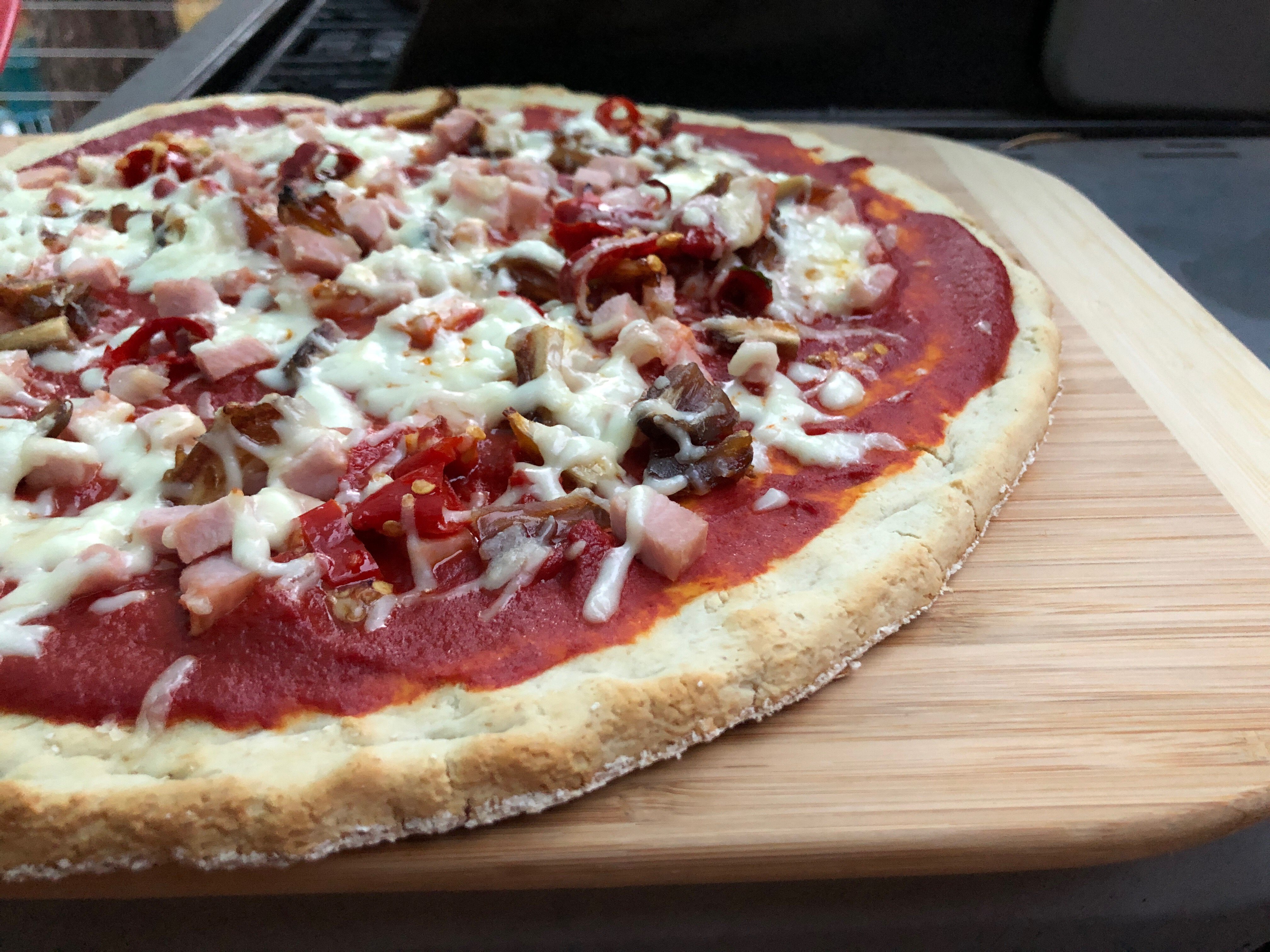 photo of a pizza on a wooden cutting board 