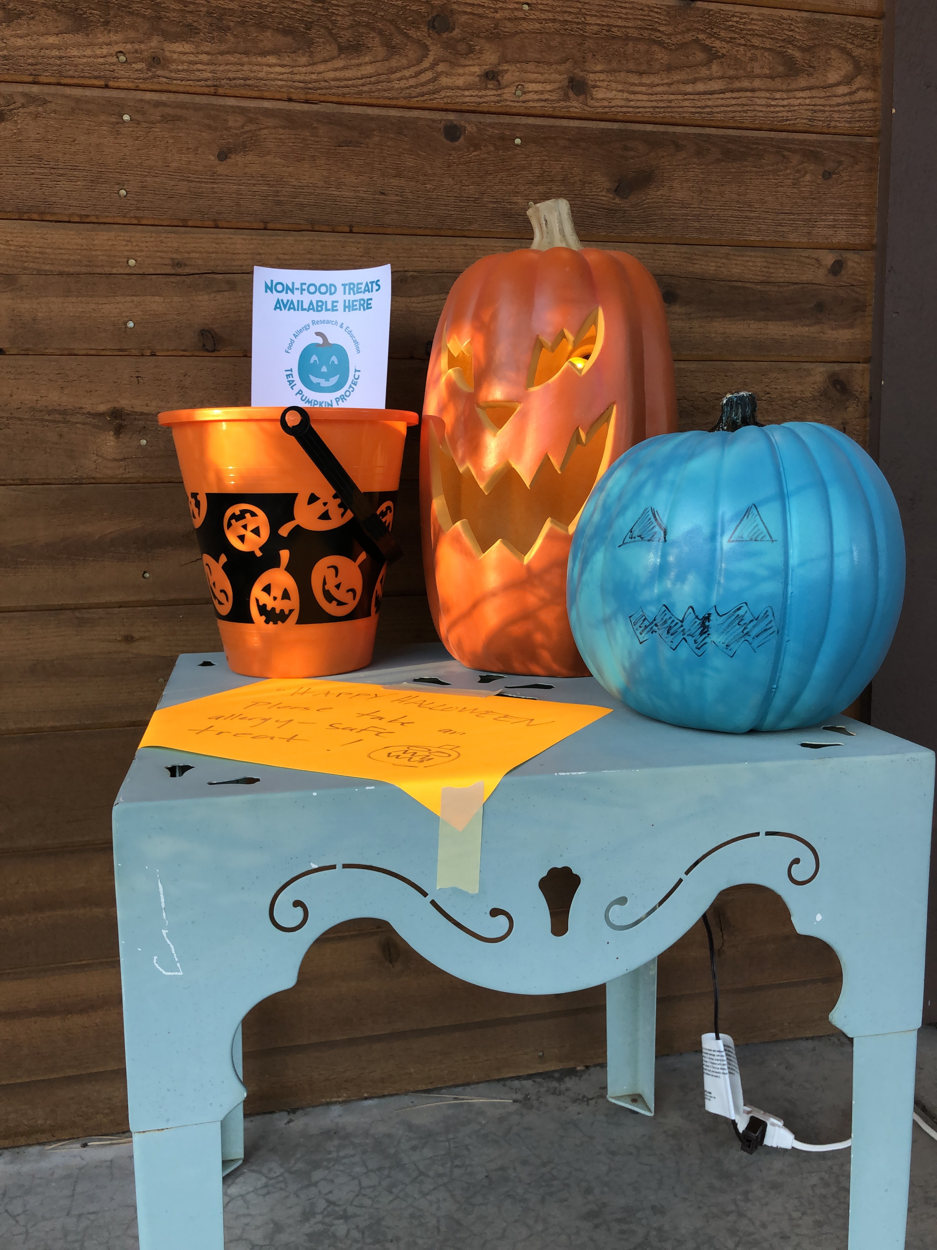 A small table with orange and teal colored pumpkins set out 