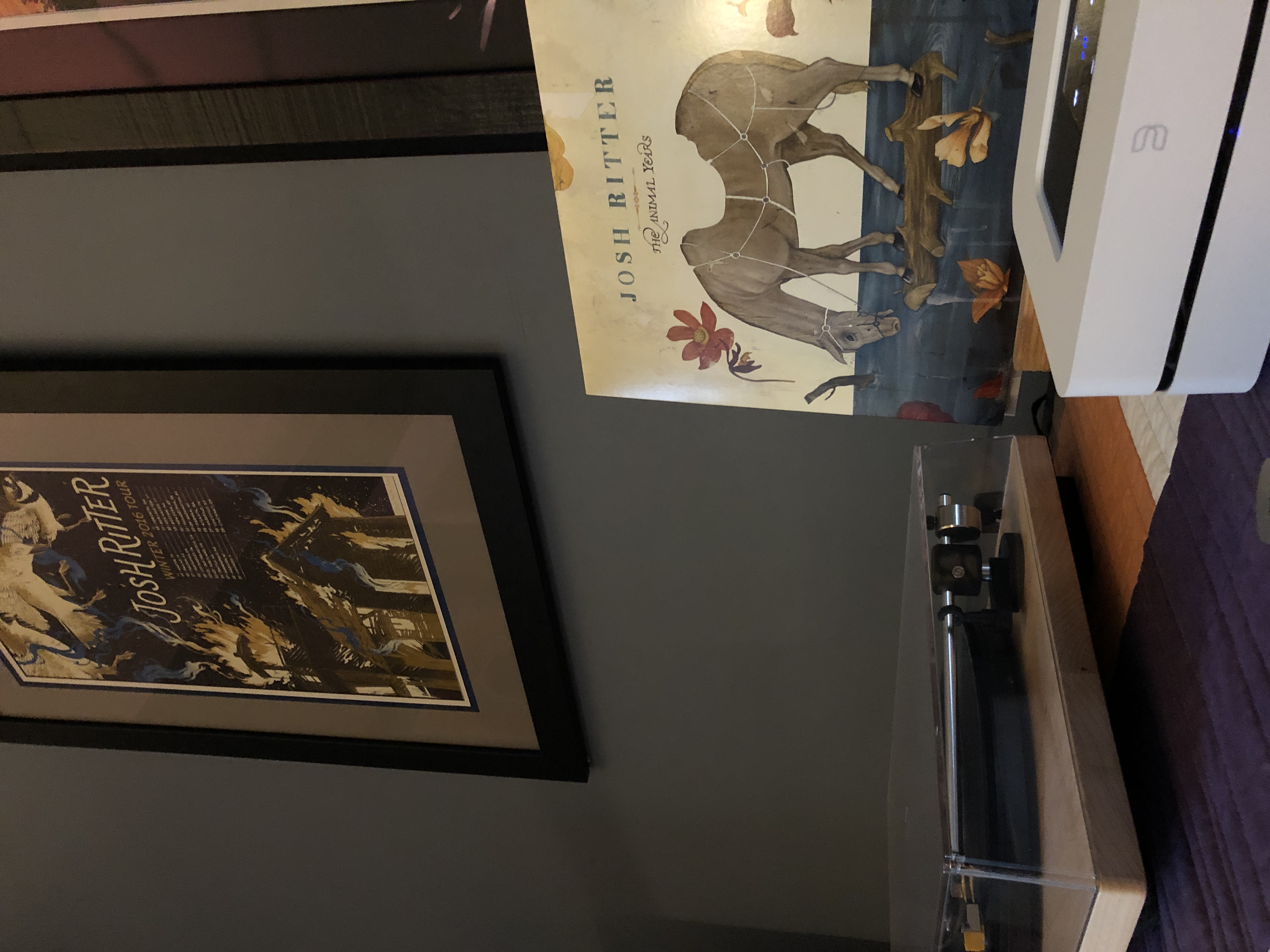 A turntable with the album cover for Josh Ritter’s The Animal Years beside it. In the background is a framed tour poster dated 2016. 
