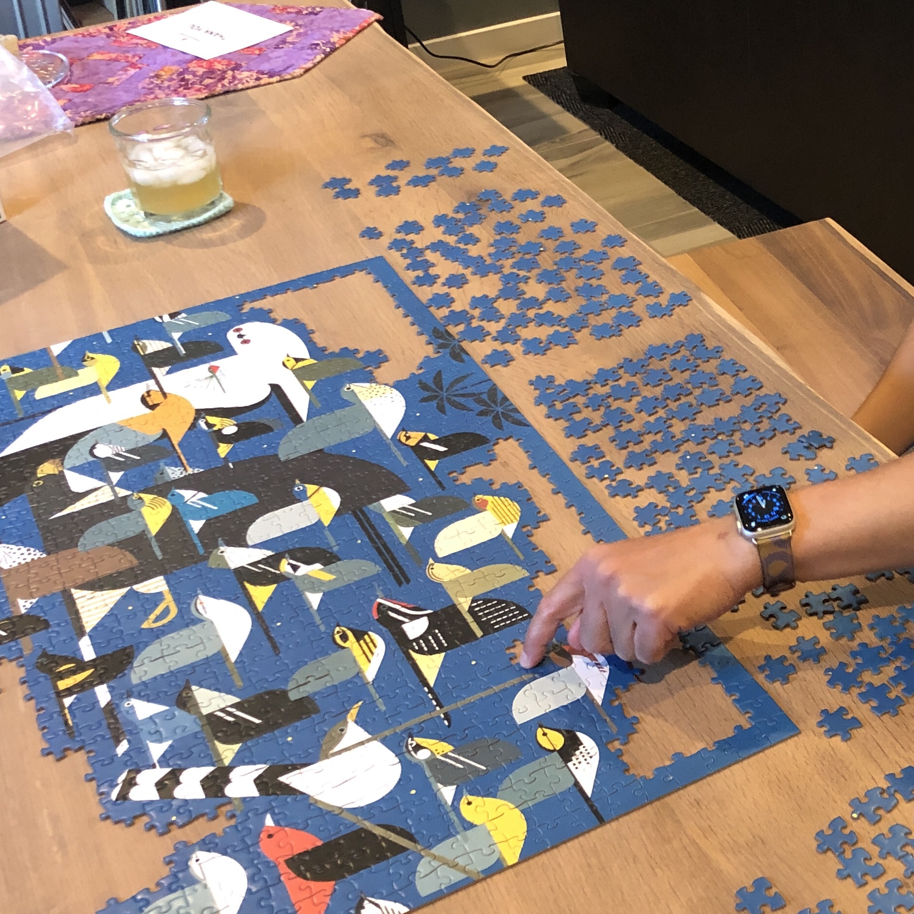 A partially completed puzzle with many neatly arranged pieces placed beside it 